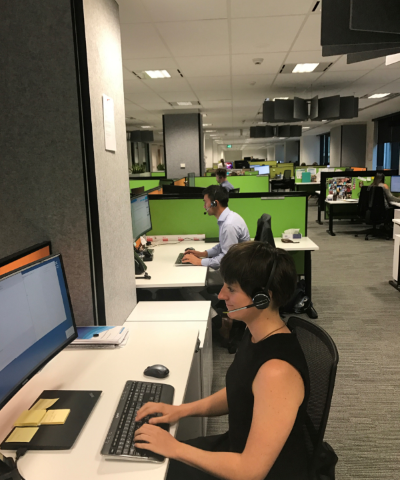 Some Ombudsman staff taking phone calls. In the foreground, a female staff member has a headset on and is typing.